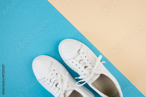 Top view of white sneakers on a blue-beige background