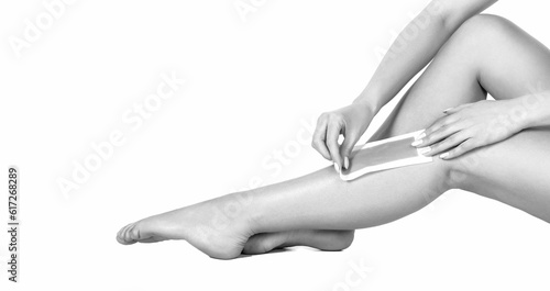 Well-groomed woman legs after epilating isolated on white background. Waxing woman leg with wax strip at beauty spa. Black and white