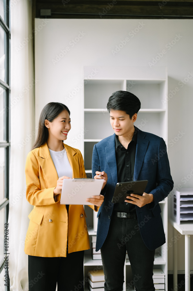 Two Asian business man and woman workers talking on the smartphone and using laptop Professionals in Teamwork Finance, Marketing, and Success Two Asian business man and woman workers talking on the smartphone and using laptop Professionals in Teamwork Finance, Marketing, and Success