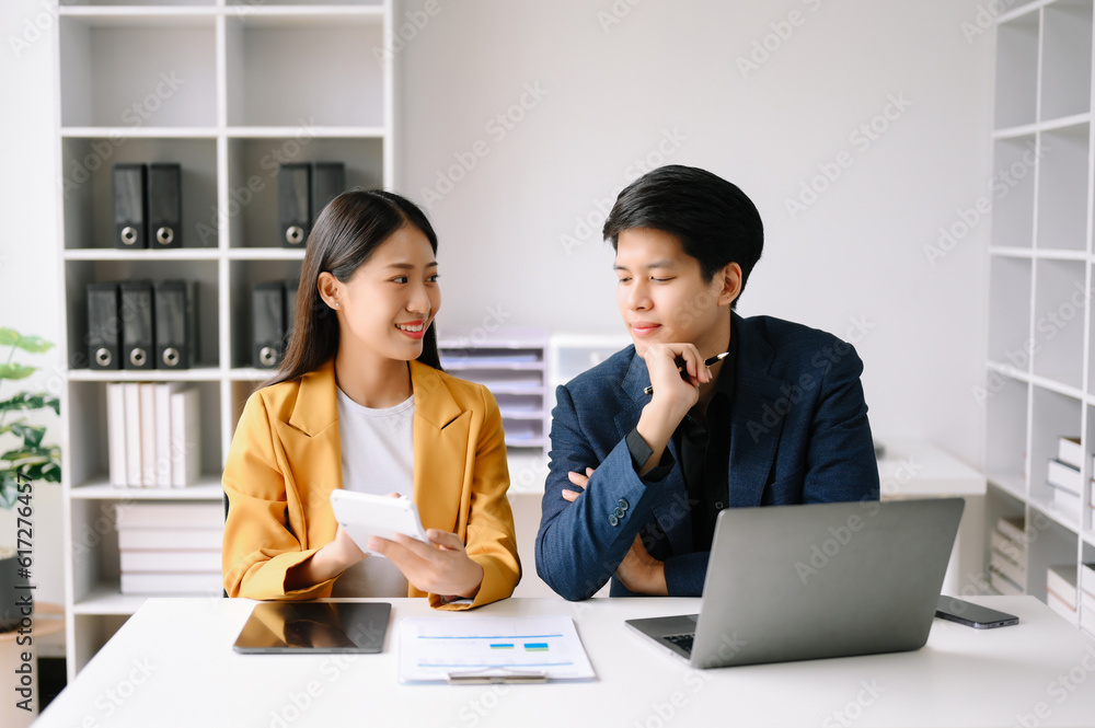 Two Asian business man and woman workers talking on the smartphone and using laptop Professionals in Teamwork Finance, Marketing, and Success Two Asian business man and woman workers talking on the smartphone and using laptop Professionals in Teamwork Finance, Marketing, and Success