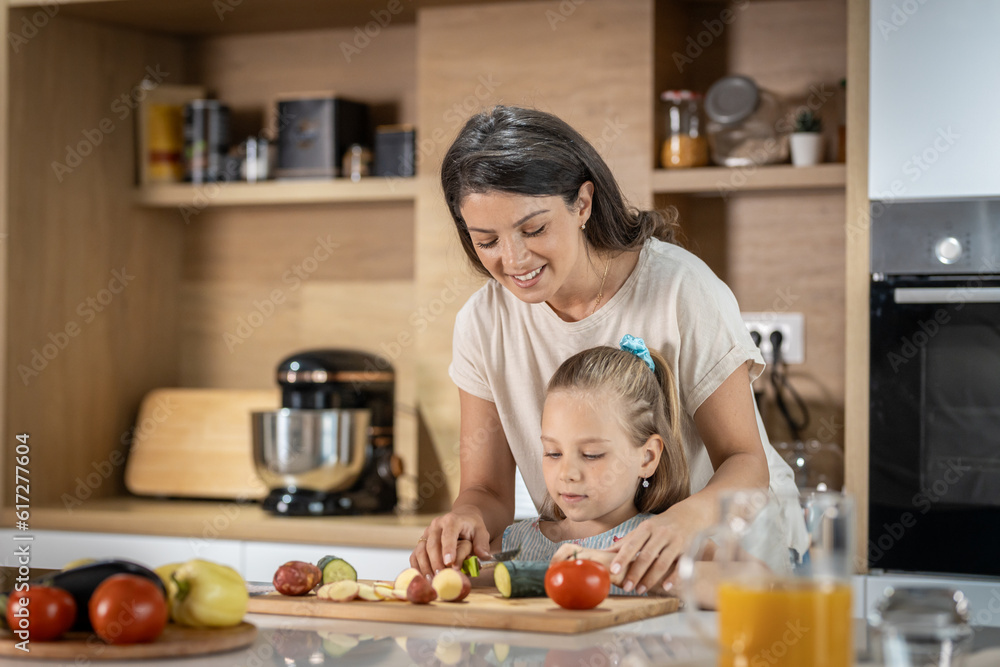 Young mother teaching her daughter how to cut vegetables Young mother teaching her daughter how to cut vegetables