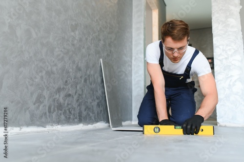 фотографія industrial worker, handyman installing big ceramic tiles