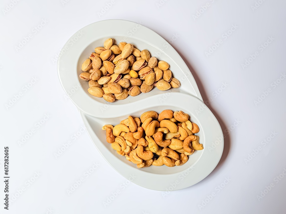 Compartmental dish with cashews and pistachios on white background. Compartmental dish with cashews and pistachios on white background.