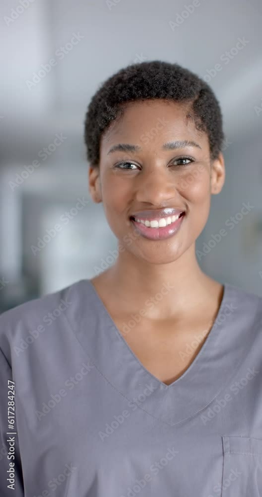 Vertical video of portrait of happy african american female doctor wearing scrubs, slow motion Vertical video of portrait of happy african american female doctor wearing scrubs, slow motion