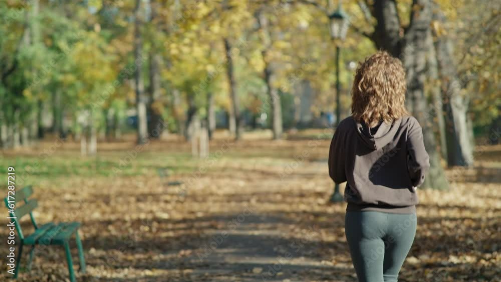 Rear view of ginger woman running at the park in autumn. Shot with RED helium camera in 8K. Rear view of ginger woman running at the park in autumn. Shot with RED helium camera in 8K.