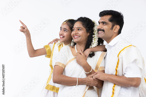 Smiling south indian parents and daughter posing in traditional clothing.