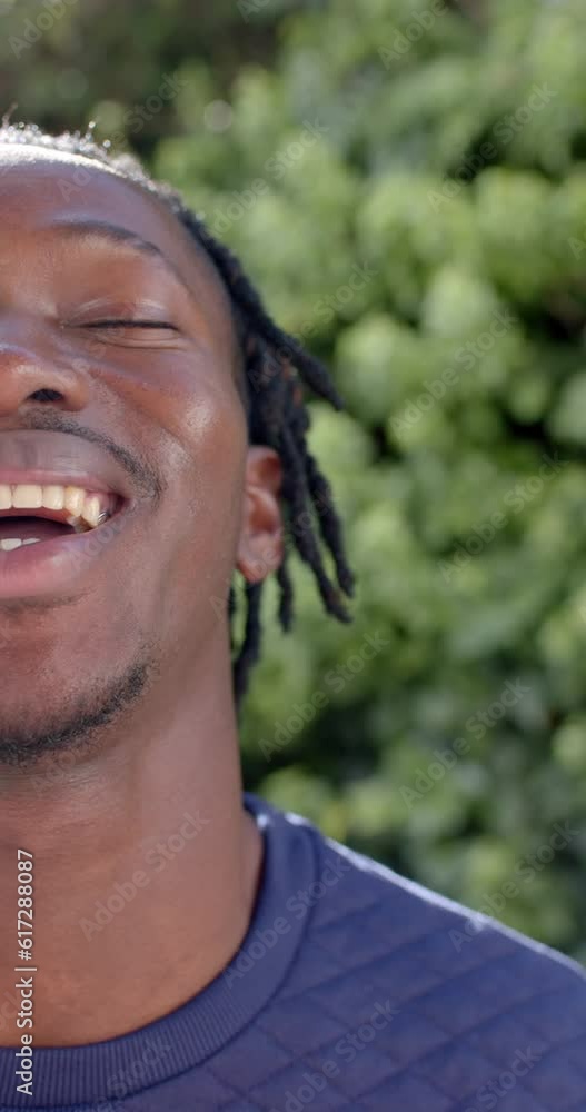 Vertical video of half portrait of happy african american man in sunny garden, slow motion Vertical video of half portrait of happy african american man in sunny garden, slow motion