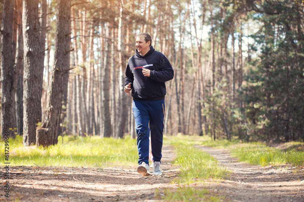 Fototapeta premium overweight man on a morning run in a sunny pine forest