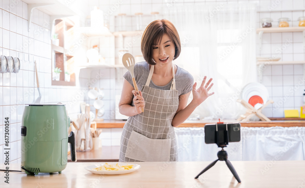 Portrait of asian chef girl cooking potato fried by Air Fryer machine in kitchen home with live camera. Work at home lifestyle. Technology eco friendly home smart device, asian housewife, minimal life Portrait of asian chef girl cooking potato fried by Air Fryer machine in kitchen home with live camera. Work at home lifestyle. Technology eco friendly home smart device, asian housewife, minimal life