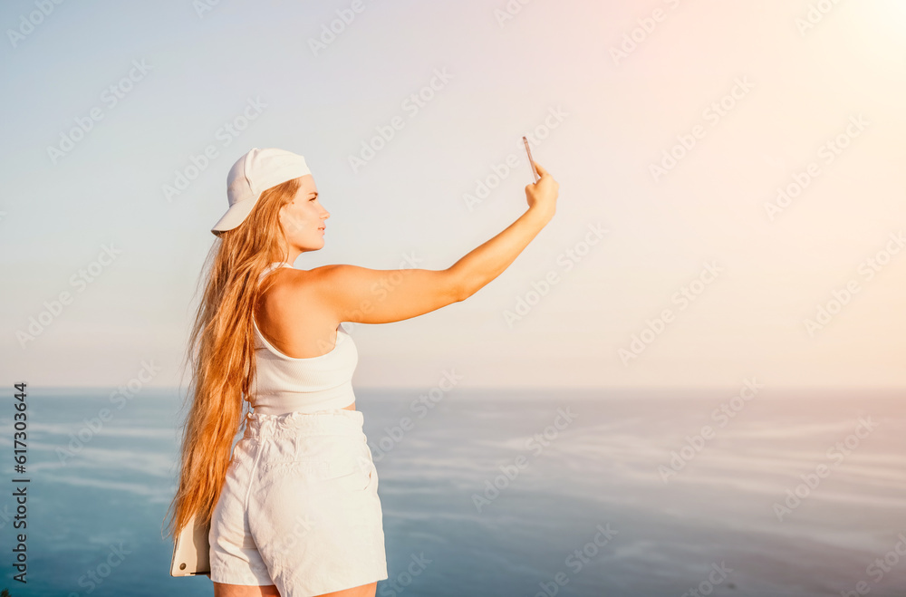 Woman travel sea. Happy tourist in hat enjoy taking picture outdoors for memories. Woman traveler posing on the beach at sea surrounded by volcanic mountains, sharing travel adventure journey Woman travel sea. Happy tourist in hat enjoy taking picture outdoors for memories. Woman traveler posing on the beach at sea surrounded by volcanic mountains, sharing travel adventure journey