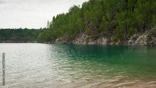 View of clear turquoise water, high cliffs with forest and artificial mountains photo