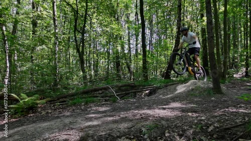 A follow-up shot of an adult male jumping on an electric bicycle on trails in the forest on at sunny day in slow motion. photo