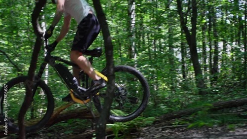 A follow-up shot of an adult male jumping on an electric bicycle on trails in the forest on at sunny day in slow motion zoomed in and focues on the bicycle. photo