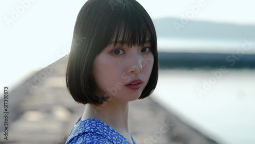 夕暮れの海を散策する青いワンピースの女性