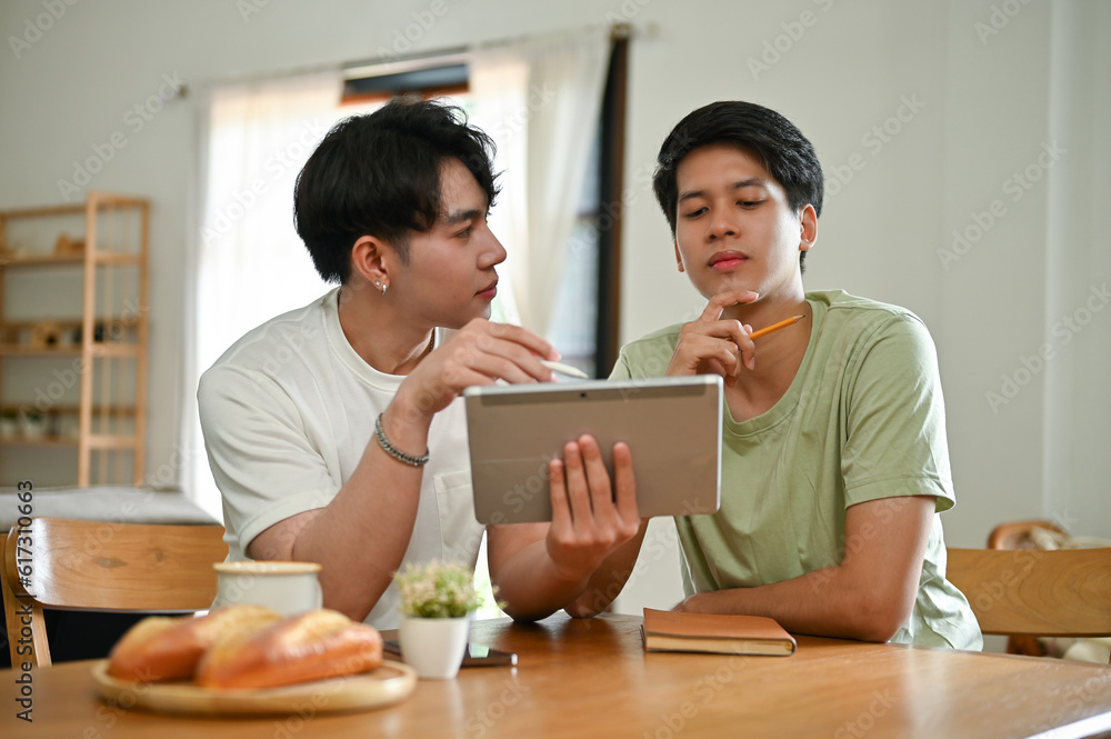 A handsome young Asian male gay couple is studying an online lesson at home together A handsome young Asian male gay couple is studying an online lesson at home together
