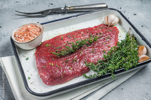 Marinatad flank beef steak with herbs and olive oil, raw meat. Gray background. Top view