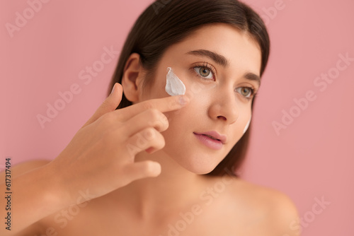 Woman applying cream on cheek