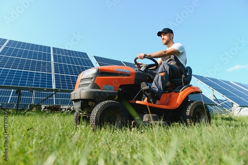A man mows the grass near the solar panels. Green energy