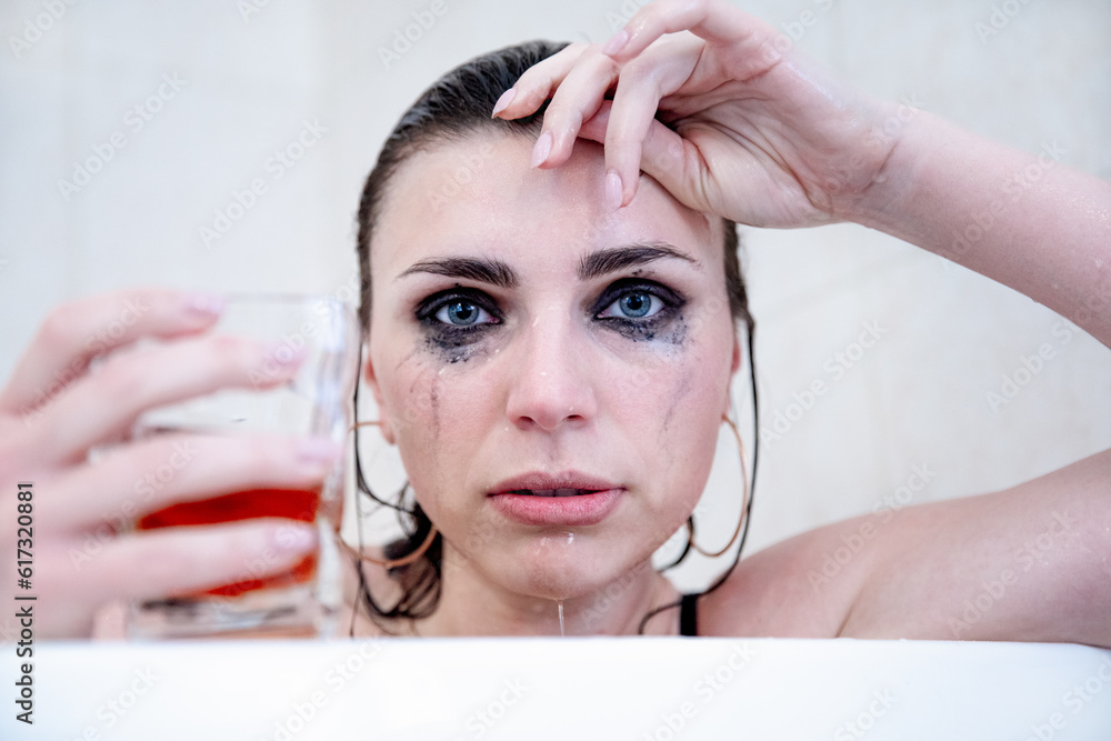 Naklejka premium Young beautiful brunette with blue eyes, heavily flowing makeup and a glass glass in her hand.