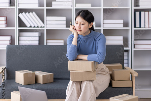 Young asian woman ecommerce SME business stressed leaning on package at home office, stressed headache Startup small business entrepreneur asian woman work package post shipping box delivery parcel