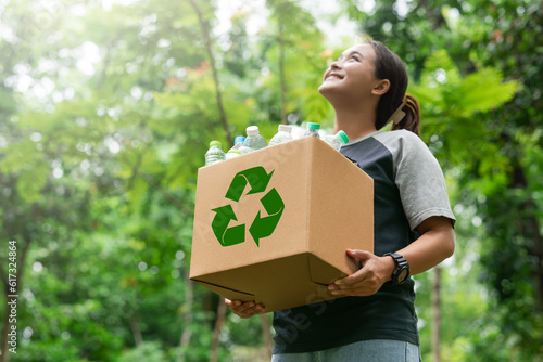 woman holding a garbage box recycling concept Recycle, recycle, plastic-free, junk food plastic packaging. on a forest nature green background