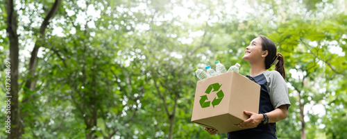woman holding a garbage box recycling concept Recycle, recycle, plastic-free, junk food plastic packaging. on a forest nature green background copy space plastic recycling Environmental pollution