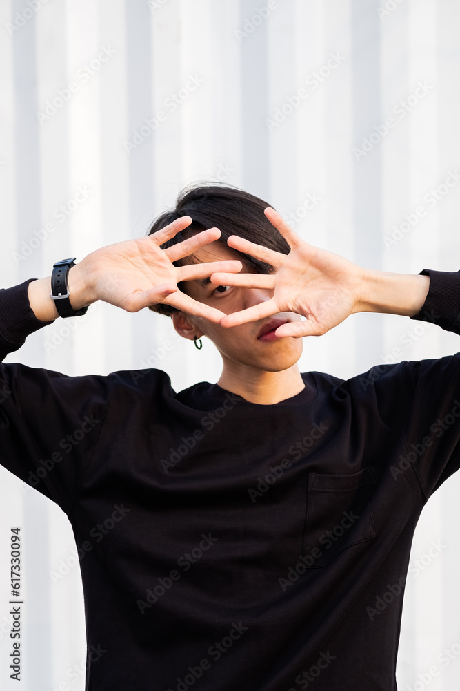 Fototapeta premium Close up portrait of extravagant asian man wearing casual clothes, posing near the wall on the street, urban lifestyle, emotional unusual