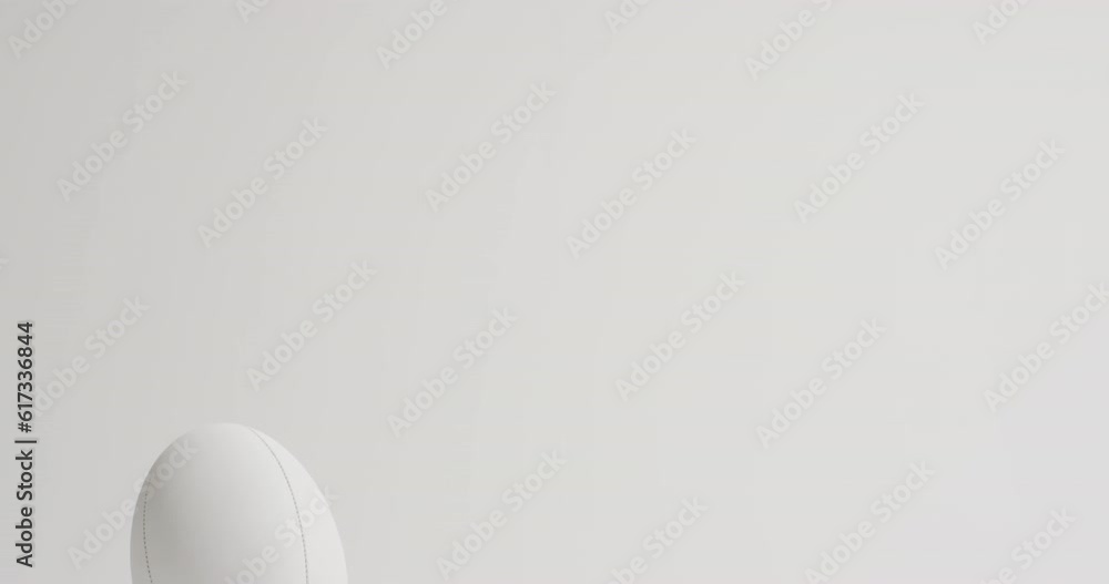 White rugby ball on kicking tee on white background with copy space, slow motion White rugby ball on kicking tee on white background with copy space, slow motion