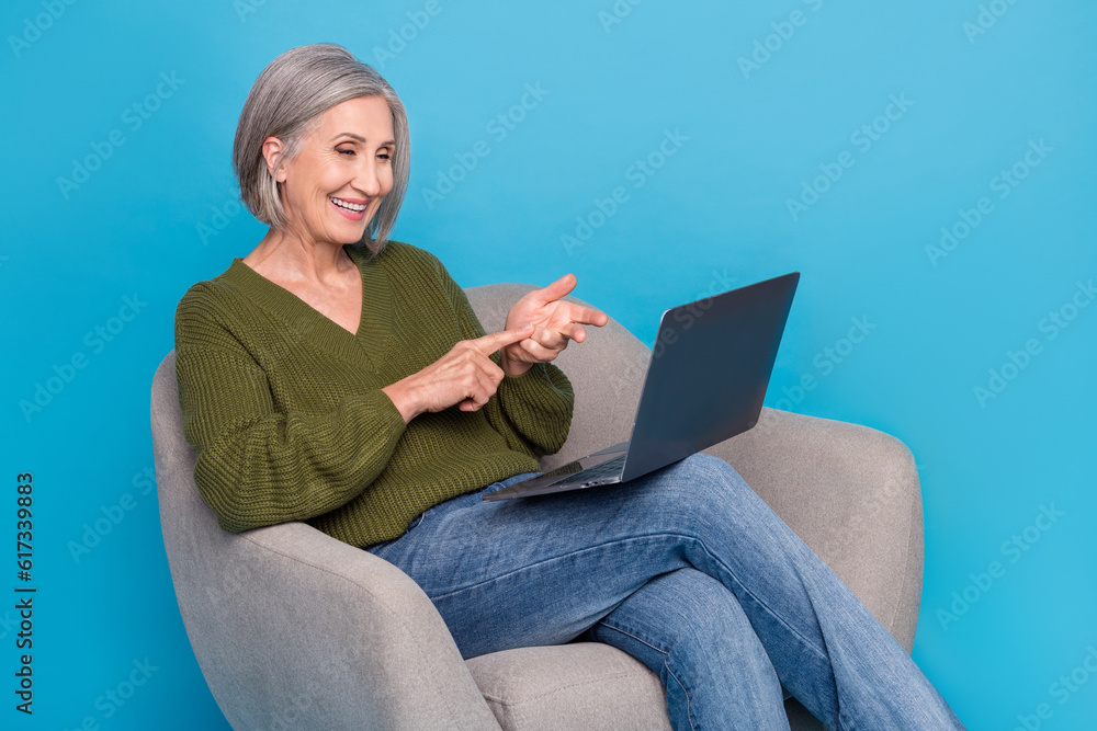 Naklejka premium Portrait of cheerful positive woman wear khaki sweater in armchair talking on webcam counting fingers isolated on blue color background