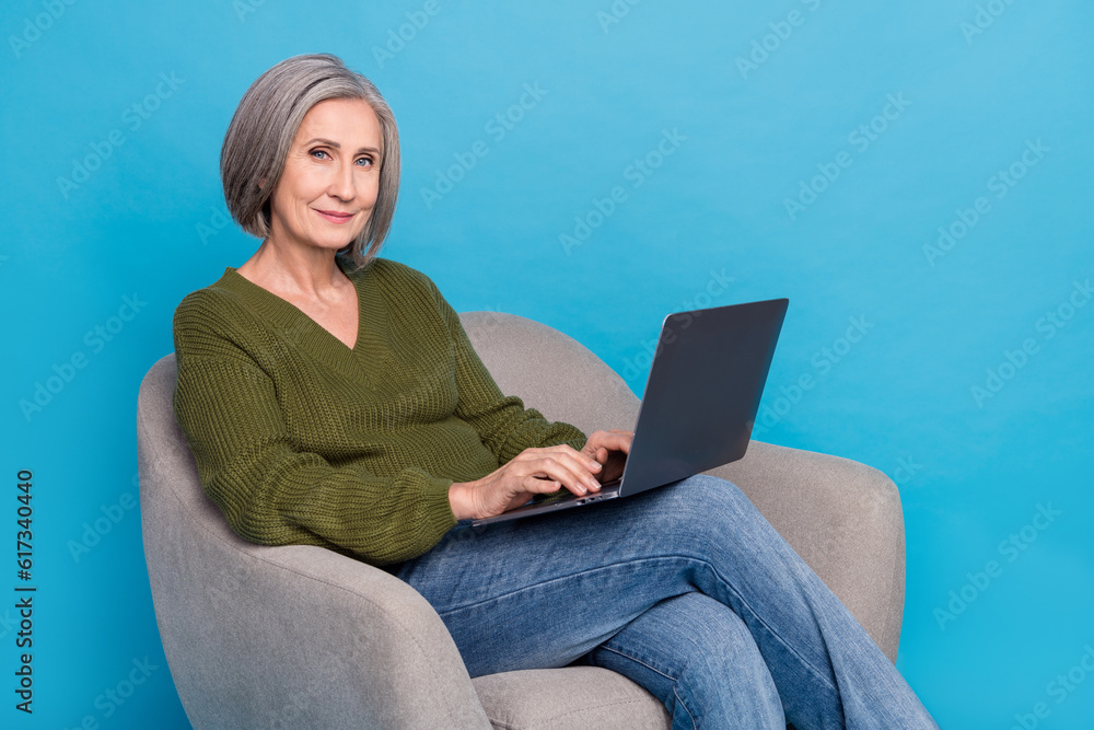 Naklejka premium Photo of good mood cheerful person wear knit pullover sitting in armchair with laptop write letter isolated on blue color background