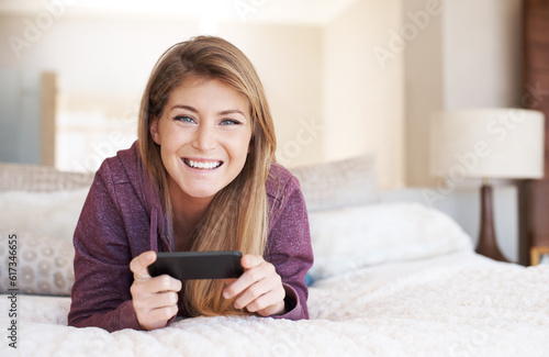 Teenager, girl in portrait and smartphone with games and relax in bedroom, smile with technology and esports. Young female person at home, gaming and mobile app with happiness, gen z and internet