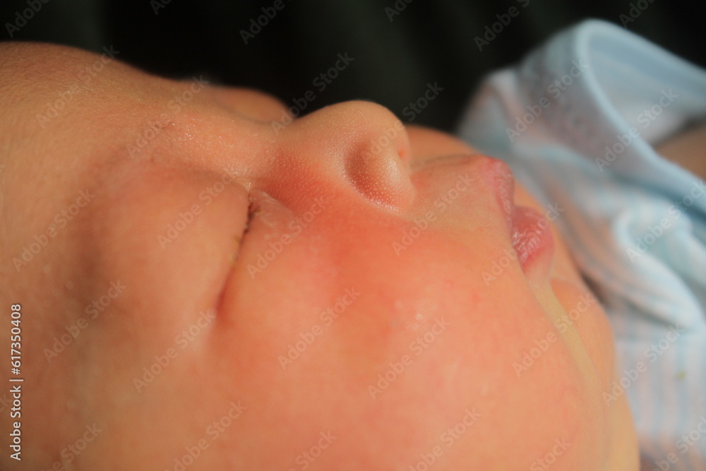 Portrait of a newborn boy who sleeps sweetly and smiles in he sleep in red clothes at a photo shoot of newborns Portrait of a newborn boy who sleeps sweetly and smiles in he sleep in red clothes at a photo shoot of newborns