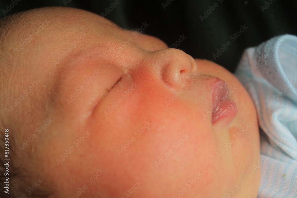 Portrait of a newborn boy who sleeps sweetly and smiles in he sleep in red clothes at a photo shoot of newborns Portrait of a newborn boy who sleeps sweetly and smiles in he sleep in red clothes at a photo shoot of newborns