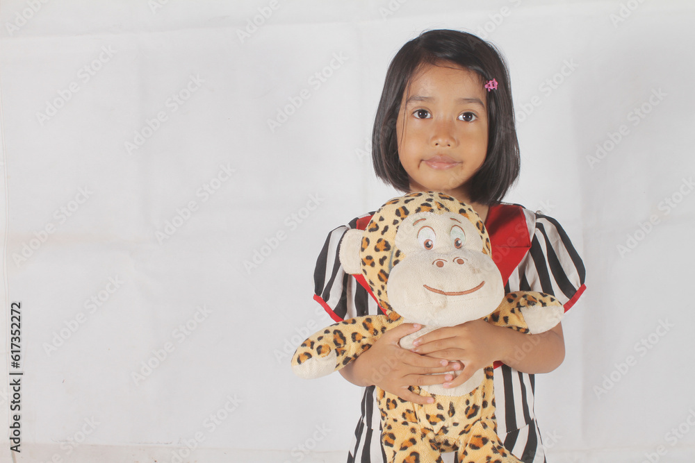 Cute Asian little girl hugging a stuffed monkey isolated on white background.
Cute Asian little girl hugging a stuffed monkey isolated on white background.