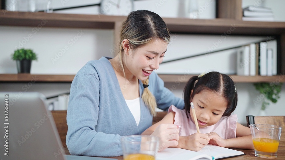 Asian mother teaching little daughter doing homework at home. Mother helping daughter doing homework. Single mother, Mother and child relationship concept Asian mother teaching little daughter doing homework at home. Mother helping daughter doing homework. Single mother, Mother and child relationship concept