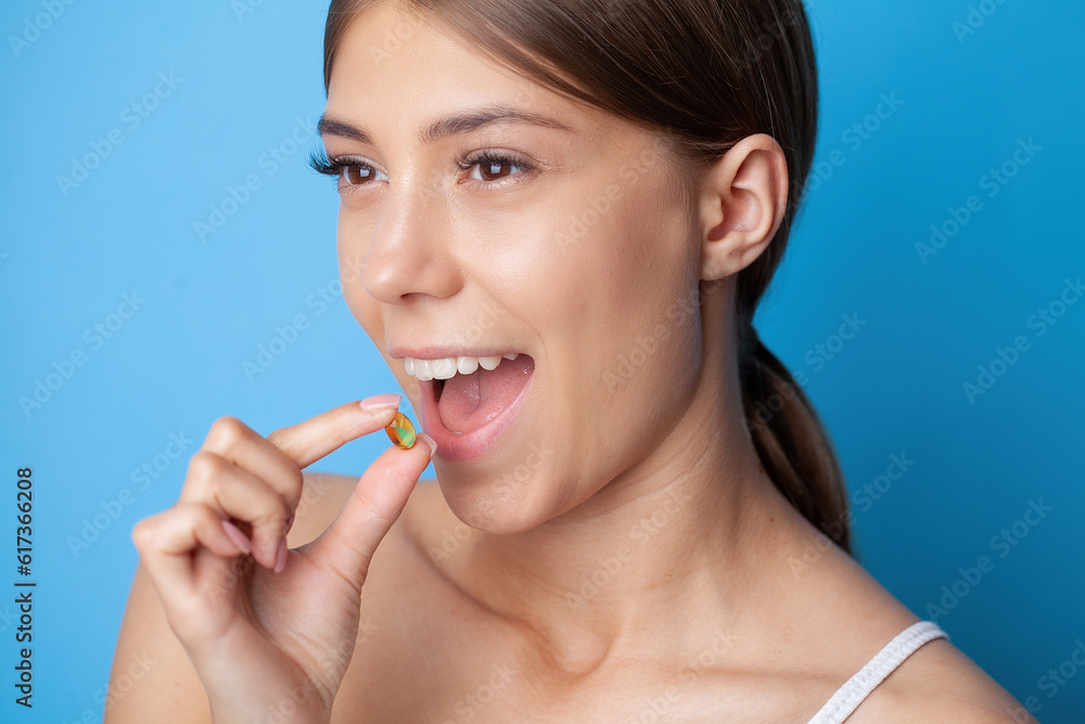 Beautiful woman holding capsule with a fish oil source of Omega-3 fatty acids Beautiful woman holding capsule with a fish oil source of Omega-3 fatty acids