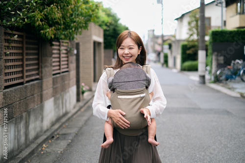 赤ちゃんを抱っこして散歩するお母さん © monzenmachi