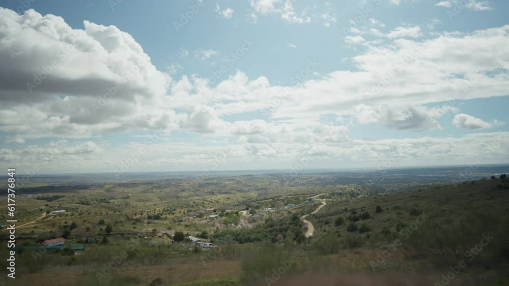 White clouds on blue spring sky over green hills in Spain. Shooting from car of picturesque landscape outdoors White clouds on blue spring sky over green hills in Spain. Shooting from car of picturesque landscape outdoors