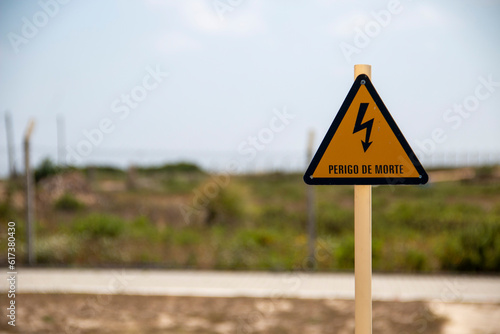 Translation: "danger of death" Electrical hazard sign, yellow triangle with a black lightning bolt inside