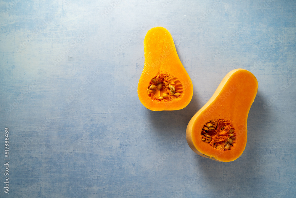 Butternut squash pumpkin halves on blue background, copy space