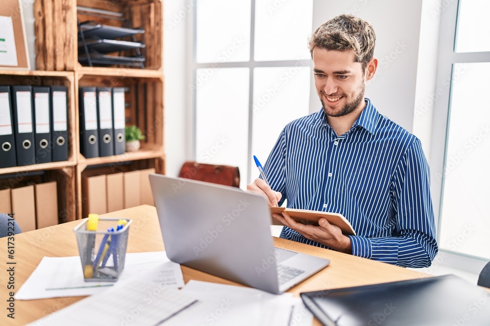 Young man business worker using laptop writing on notebook at office Young man business worker using laptop writing on notebook at office