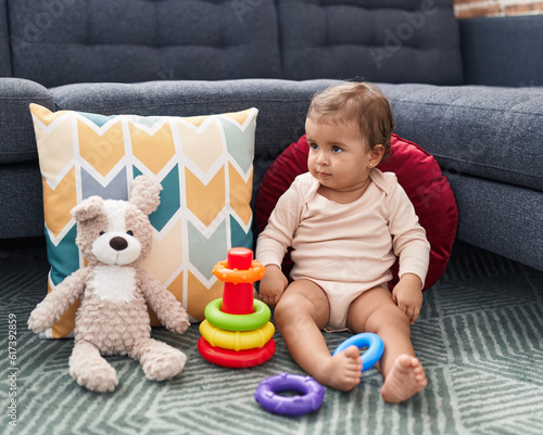 Adorable hispanic baby playing with hoops game sitting on floor at home