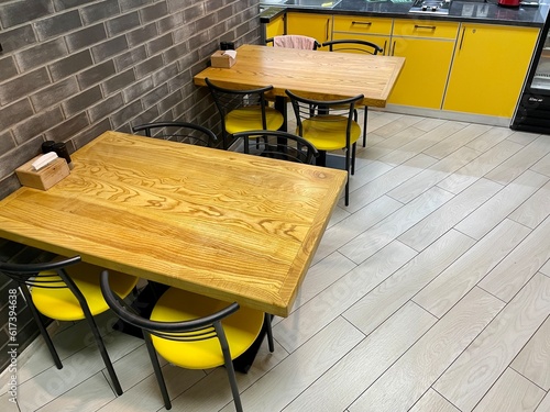 The table in the kitchen. Kitchen in the hostel. Table and chairs. Yellow chairs. Kitchen furniture. Kitchen. a large wooden table with a white and black chairs