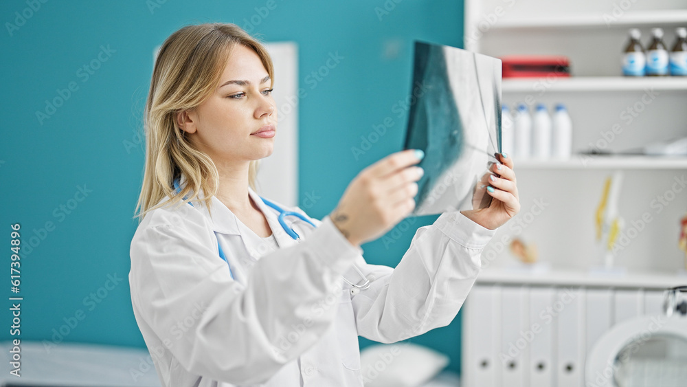 Young blonde woman doctor looking xray thinking at clinic Young blonde woman doctor looking xray thinking at clinic