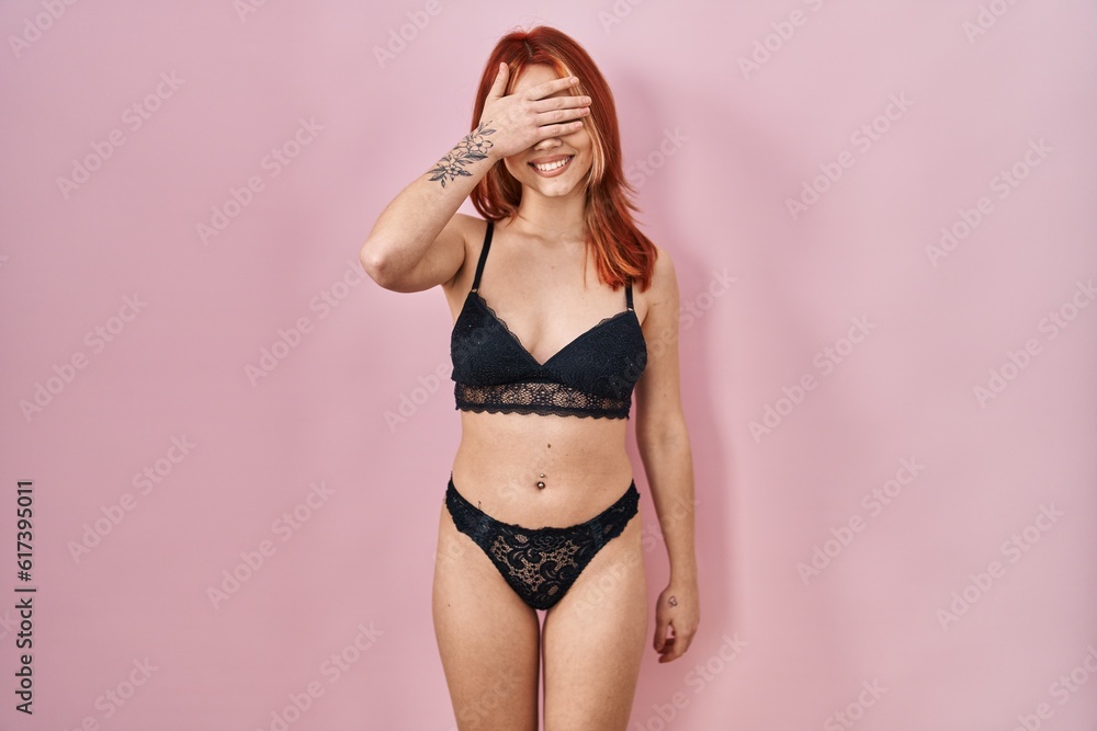 Obraz premium Young caucasian woman wearing lingerie over pink background smiling and laughing with hand on face covering eyes for surprise. blind concept.