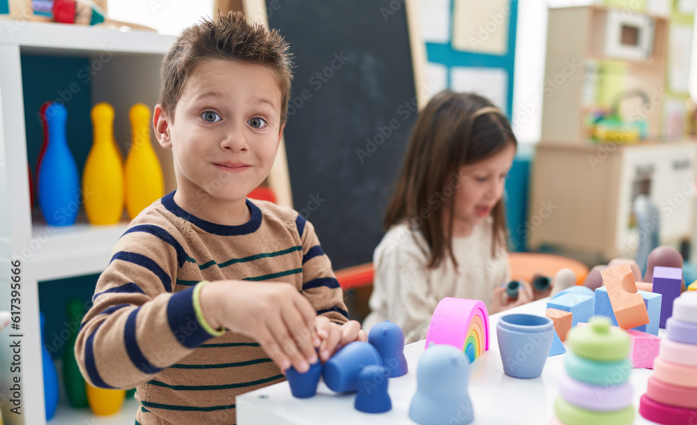 Adorable boy and girl playing with construction blocks sitting on table at kindergarten Adorable boy and girl playing with construction blocks sitting on table at kindergarten