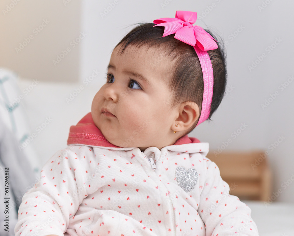 Adorable hispanic baby sitting on bed with relaxed expression at bedroom Adorable hispanic baby sitting on bed with relaxed expression at bedroom