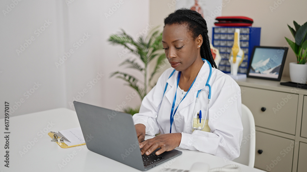 African american woman doctor using laptop working at clinic