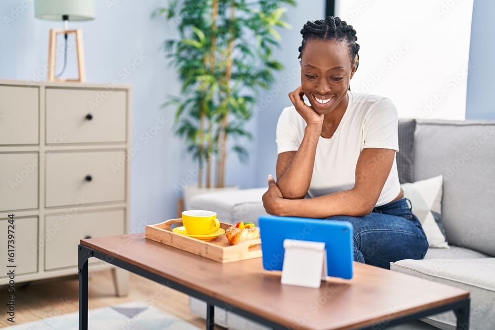 African american woman having breakfast watching video on touchpad at home African american woman having breakfast watching video on touchpad at home