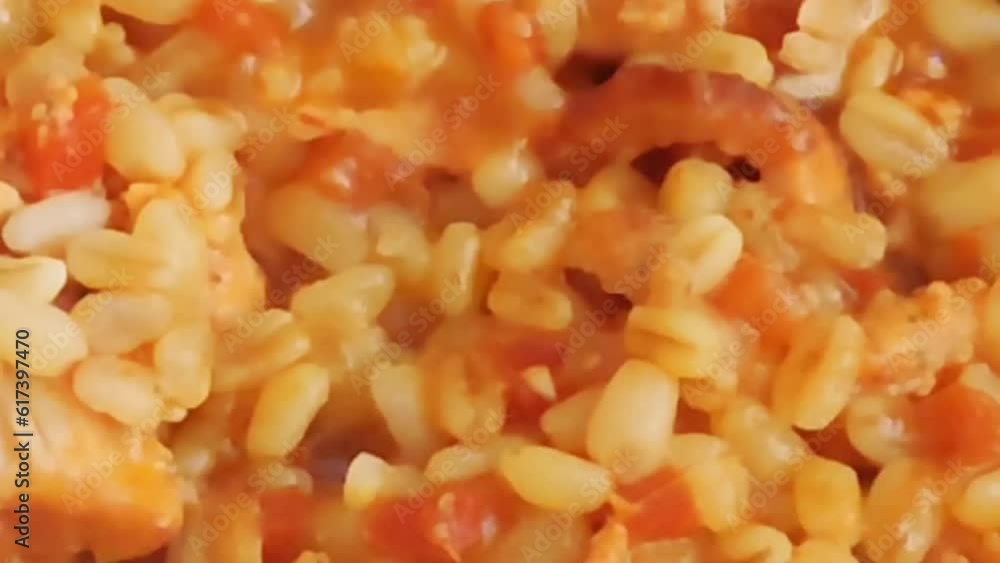 Natural orange bulgur with chicken pieces is stewed in a black frying pan Natural orange bulgur with chicken pieces is stewed in a black frying pan